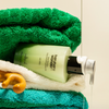 Green bottle of body wash on a towel with a green towel in the background