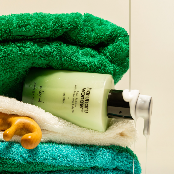 Green bottle of body wash on a towel with a green towel in the background
